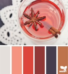 a glass filled with red liquid and cinnamon sticks on top of it, next to a white doily