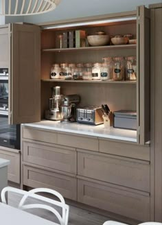 a kitchen with lots of cupboard space and white chairs