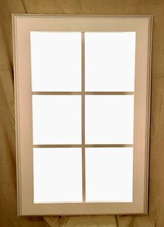 a white window with four panes on the outside and one in the inside, against a tan background