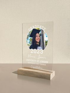 a clear acrylic plaque with a graduation photo on it and a wooden stand