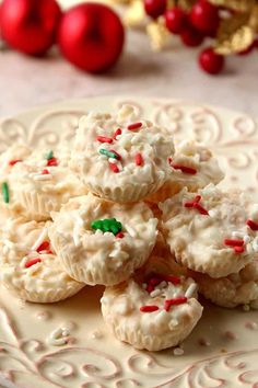 cookies with white frosting and sprinkles on a plate next to christmas decorations