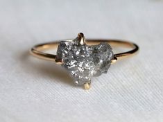 a close up of a diamond ring on a white surface with one stone in the middle