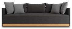 a black couch with grey pillows and wooden frame