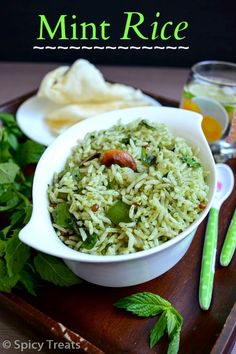 a white bowl filled with rice and vegetables on top of a wooden tray next to green leaves