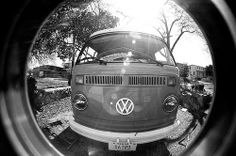 an old vw bus parked in front of a house with the hood up on