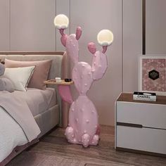 a pink cactus lamp sitting on top of a bed next to a night stand and nightstand