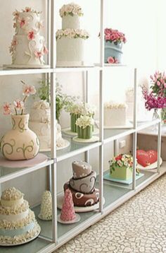 many different types of cakes on shelves in a room with white walls and carpeted flooring