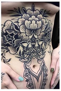 a woman's stomach with tattoos on it and flowers in the middle of her stomach