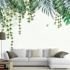 a living room with white couches and green plants on the wall