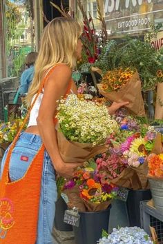 a woman standing in front of a flower shop with lots of flowers on the counter