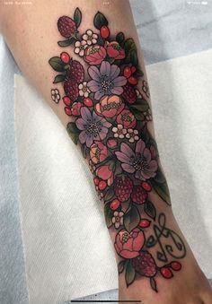 a woman's foot with flowers and berries tattooed on the side of her leg