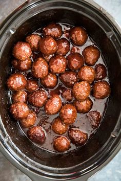 meatballs are being cooked in the crockpot with brown liquid on top, ready to be eaten