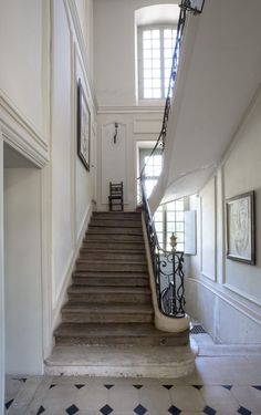 the stairs are made of wood and have wrought iron railings on each side, along with framed pictures above them