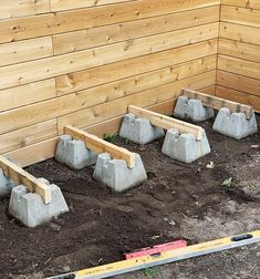 concrete blocks are placed in the ground near a wooden wall