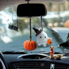 two crocheted pumpkins hanging from hooks in the front seat of a car