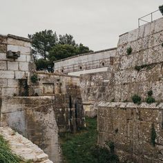 an old stone building with grass growing on the walls and in between it is another brick structure