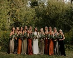 a group of women standing next to each other in front of some trees and bushes