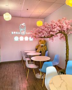 a teddy bear sitting on top of a table in a room with chairs and tables