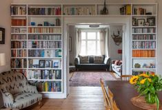 a living room filled with lots of furniture and bookshelves next to a window