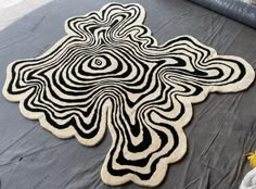 a black and white rug on the ground with an artistic design in the shape of a cross