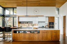 a kitchen with wooden floors and white walls, along with an island that has seating for four