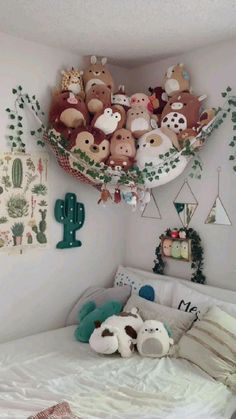 a bed with stuffed animals on the headboard and hanging decorations above it in a bedroom