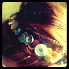 a close up of a woman's hair with buttons on it and her hair in a pony tail