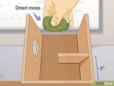 a hand is cleaning the bottom of a wooden box with a green rag on it