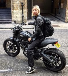 a woman is sitting on a motorcycle in the street