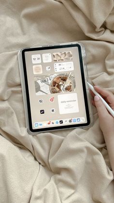 a person is holding a pen and looking at an electronic device on a bed with sheets