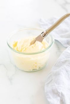 a glass bowl filled with whipped cream next to a spatula on a marble counter