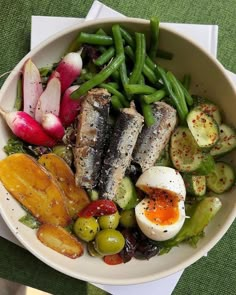 a white bowl filled with different types of food on top of a green table cloth