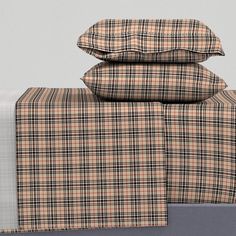 three plaid sheets are stacked on top of each other, with two pillow cases in the background