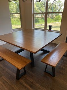 a wooden table with two benches in front of large windows and wood flooring area