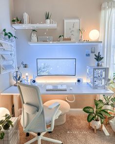 a white desk with a computer on it and some plants in front of the monitor