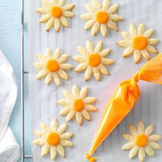 the cookies are decorated with yellow icing and orange decorations on top of white paper