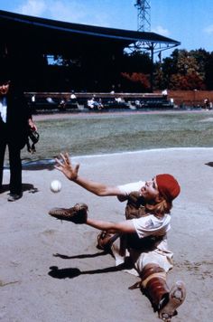 a baseball player sliding into home plate to catch the ball while another man looks on