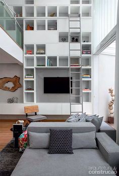 a living room filled with furniture and a tall white book shelf next to a tv