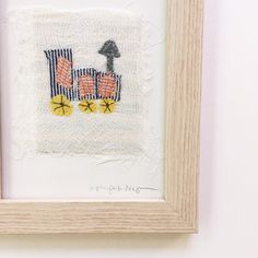 an embroidered picture hanging on the wall next to a wooden frame