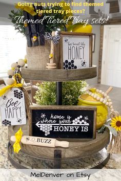 a three tiered tray with signs and flowers on the top that says, what does it mean to be happy?