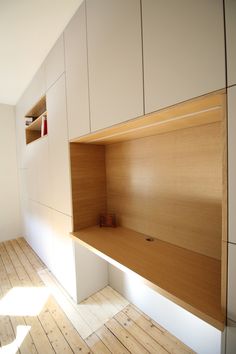 an empty room with wooden flooring and white cupboards on the wall above it