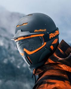 a person wearing a black and orange jacket with a helmet on top of their head