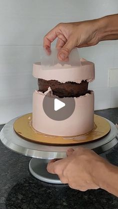 someone is decorating a cake with pink icing and chocolate frosting on top