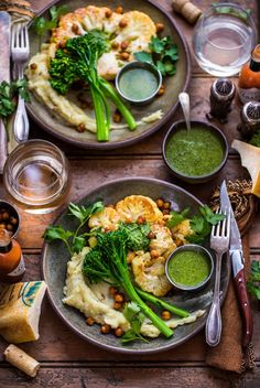 two plates filled with different types of food on top of a wooden table next to glasses and utensils