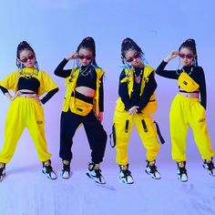 four girls in yellow and black outfits posing for the camera with their hands on their hipss