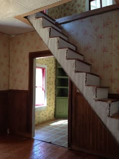 an open door leading to a room with floral wallpaper on the walls and wooden stairs