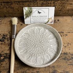 a white plate sitting on top of a wooden table next to a brush