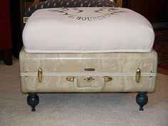 an old suitcase sitting on top of a footstool in the middle of a room