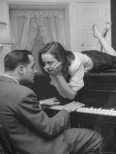 a man sitting next to a woman on top of a piano