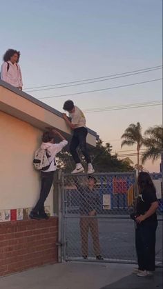 three people standing on top of a building while one person is doing skateboard tricks